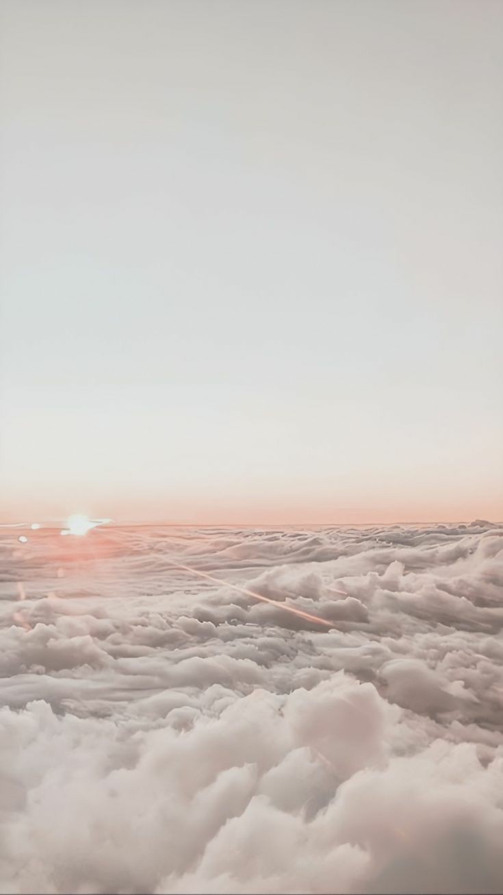 sky from above the clouds with the sun setting over the horizon